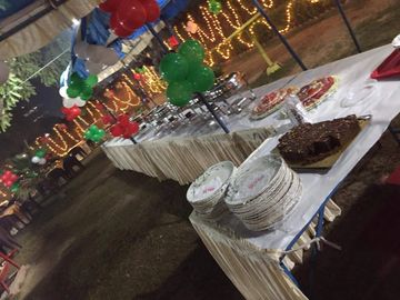 Outdoor party setup with colorful balloons and food tables at night.