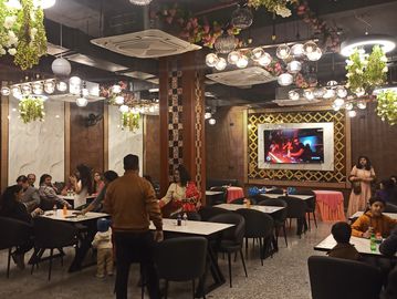 People dining in a warmly lit, decorated restaurant with floral ceiling accents.