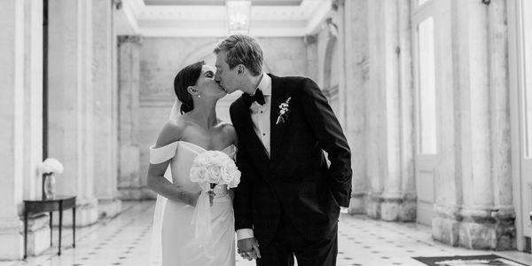 Bride and groom share a kiss in a grand hall on their wedding day.