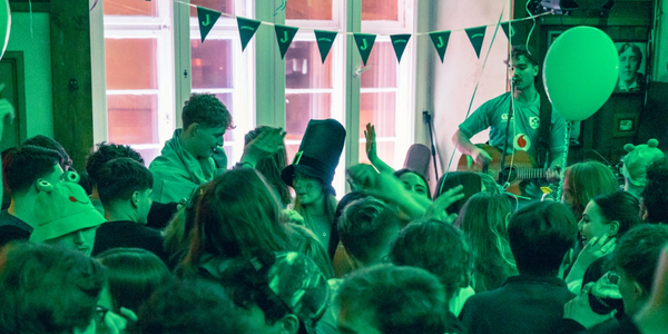 Crowded indoor party with people enjoying live music and festive decorations.