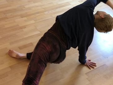 Kathleen Rea kneels on one knee while reaching into a side bend with her arm overhead.