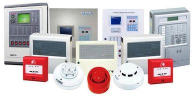 Various fire alarm control panels and detectors arranged in a row.