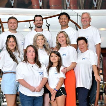 Group photo of smiling people wearing matching white shirts indoors.