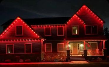 A house decorated with red lights along the roof and windows at night.