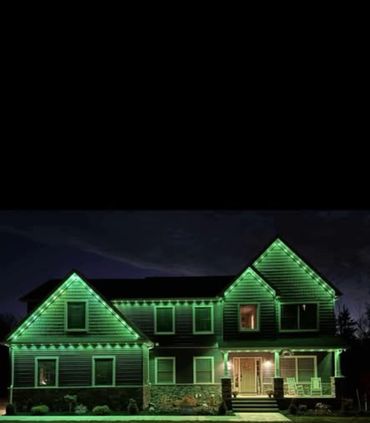 House decorated with green Govee Christmas lights outlining the roof and porch at night.