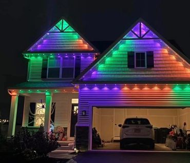 House decorated with colorful Halloween lights and a giant spider on the porch.