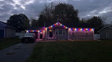 House decorated with red, white, and blue lights at dusk.