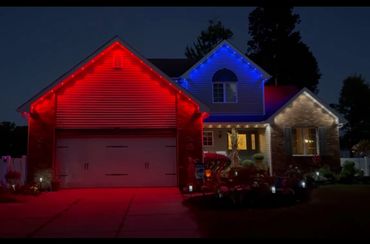 House decorated with red, blue, and white exterior lights at night.