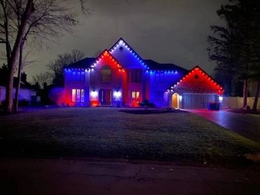 House decorated with red, white, and blue lights at night.