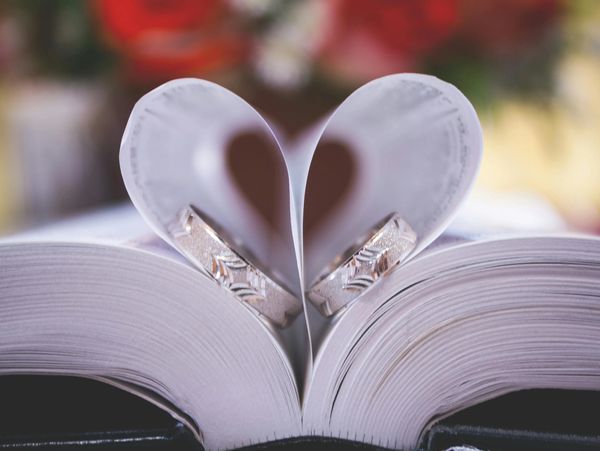 A closeup of wedding rings forming heart shapes on the bible - concept of love and marriage