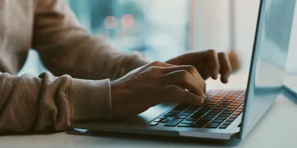 Person typing on a laptop keyboard.
