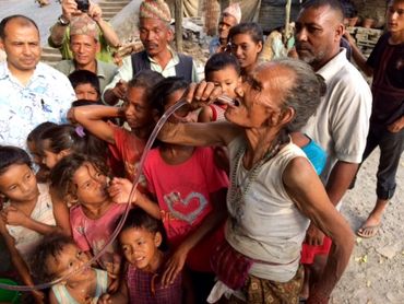 Older Woman drinking water from the Air Mobile Rescuer in Napaule after an Earthquake.