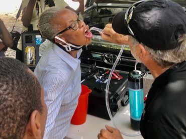 Older lady drinking water from the Air Mobile Rescuer Water Purifier with Joe in Haiti.