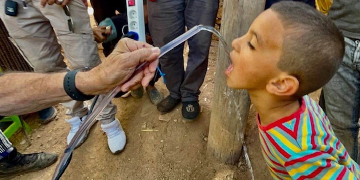 A boy drinking water from the Air Mobile Rescuer.