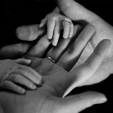 Picture of adult hands holding a baby's hands.