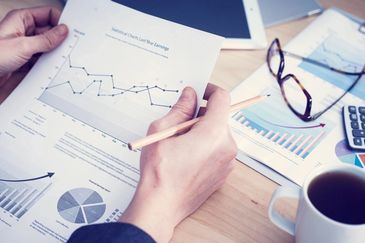 A person reading the graphs with a cup of coffee