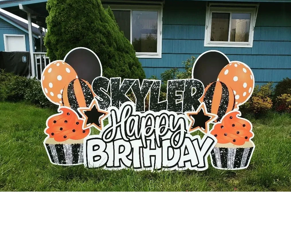 Happy Birthday lawn sign, cupcakes and balloons in orange, black and silver.