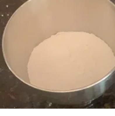 Bowl filled with white powder, likely flour, on a kitchen counter.