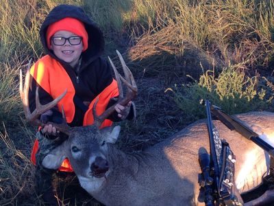 young boy child with buck deer after hunt