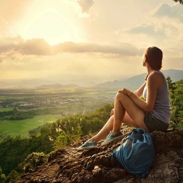 Woman sitting on a mountain overlooking a beautiful valley.