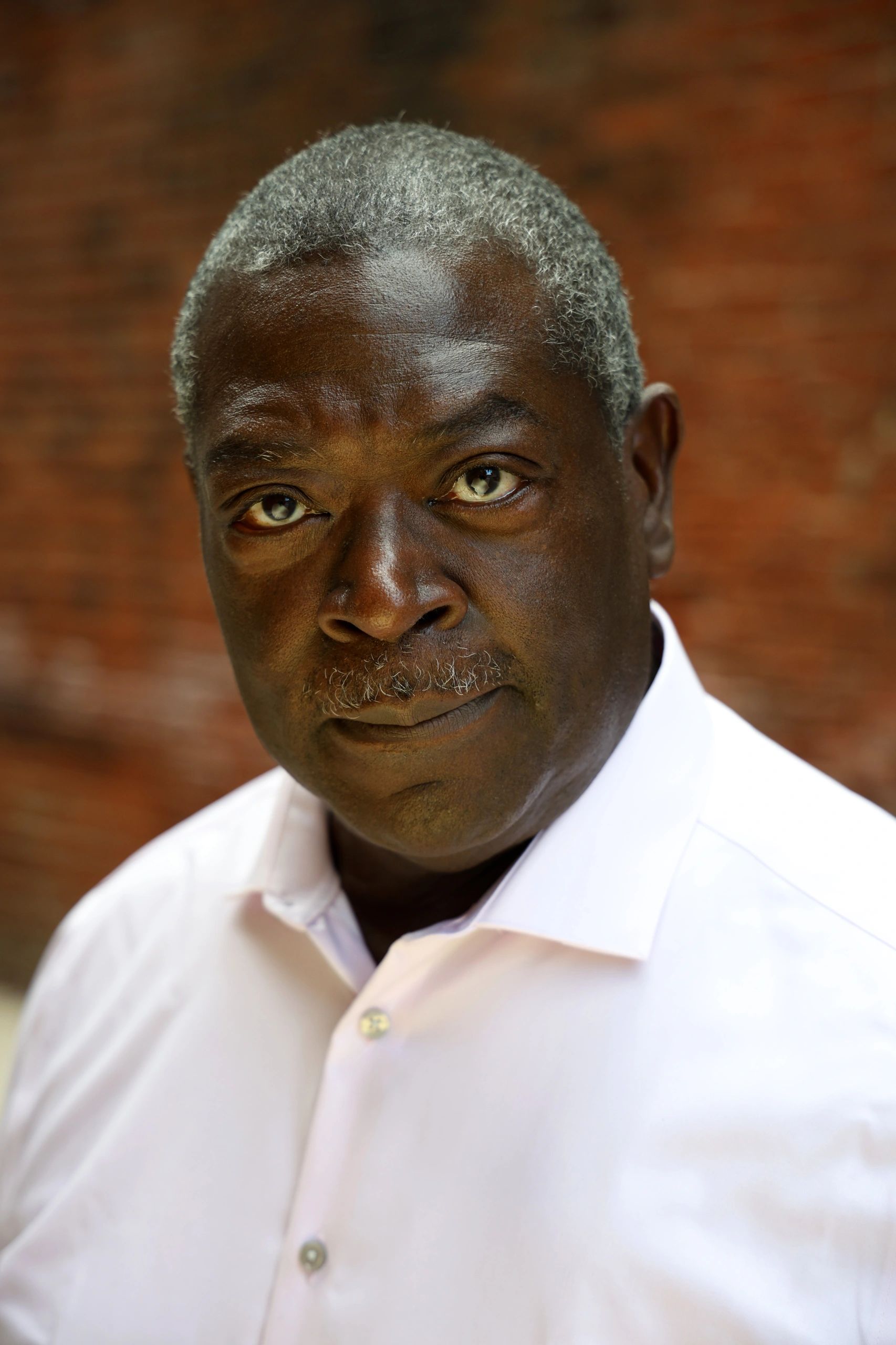 Portrait of a serious middle-aged man with graying hair in a white shirt.