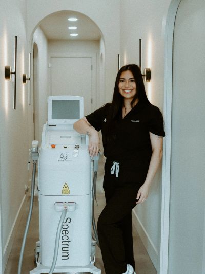 Woman in black scrubs standing next to a Spectrum medical device in a hallway.