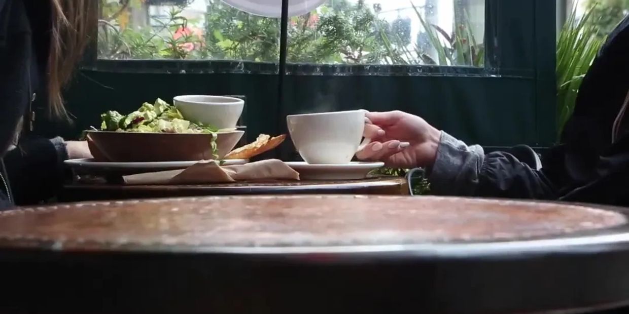 Two people sharing coffee and salad at a cozy cafe table.