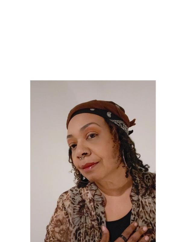 Woman with curly hair wearing a brown headscarf and animal print shawl.