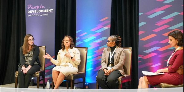 Four women panelists engaged in a development summit discussion.