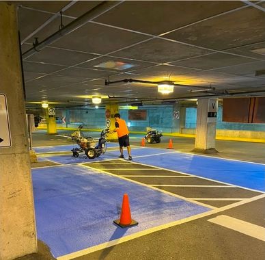 Person in orange shirt working on a go-kart in a parking garage.