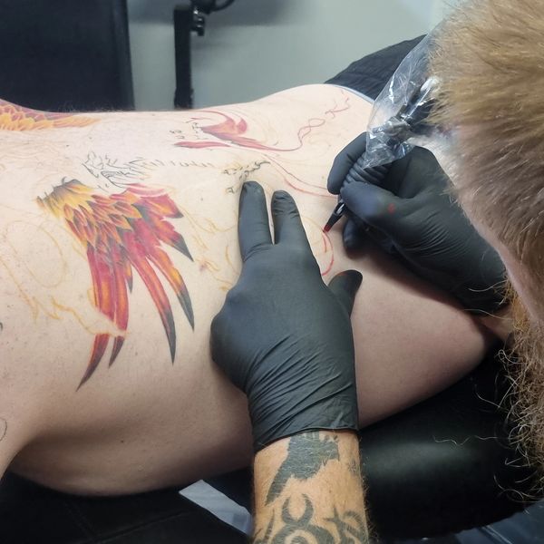 Tattoo artist working on a full colour back piecè