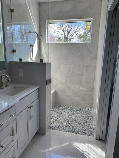 Modern bathroom with pebble stone shower floor and large window.