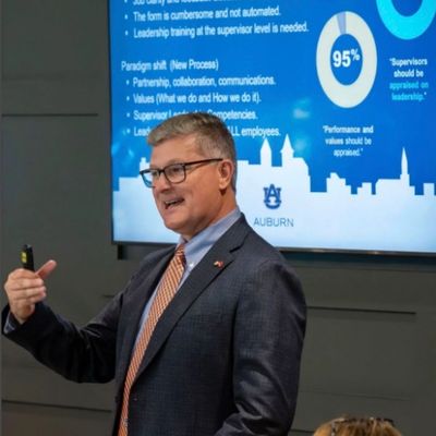 Man in suit giving a presentation with Auburn University slide behind him.