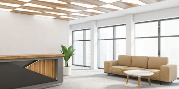 Modern office reception area with sofa and wooden desk.
