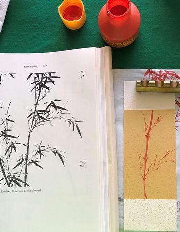 Artistic bamboo illustrations with paint jars on a green table.