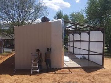 Installing insulation and metal sheeting on a garage being built by Outdoors Construction.