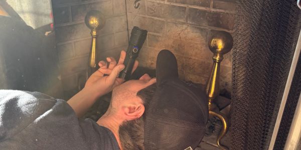 Person inspecting a fireplace with a flashlight.