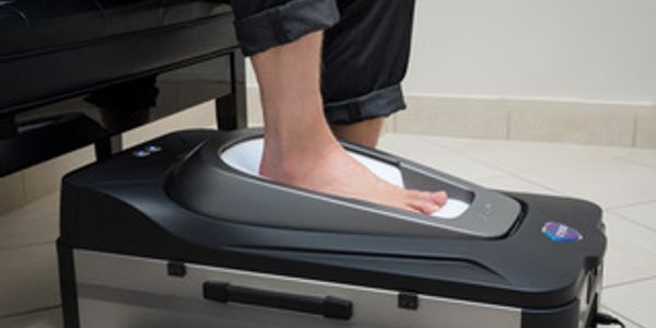woman with foot on Cryos custom orthotics scanning machine
