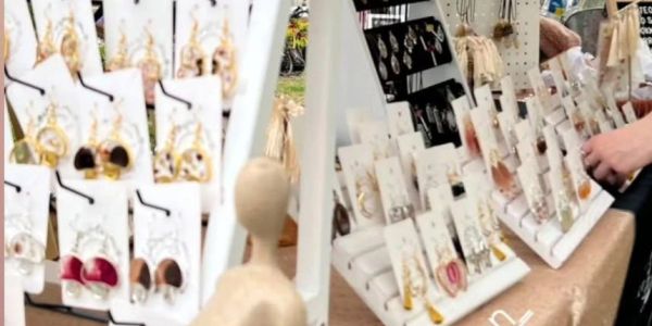 Display of various earrings on white racks at a market stall.