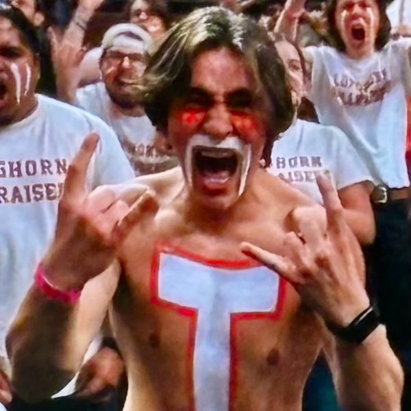 Excited shirtless fan with face paint cheering at a sports event.