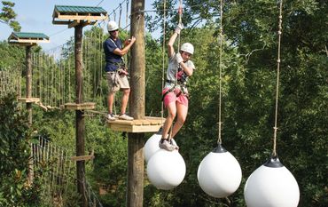 College students enjoying a team-building activity on aerial adventure park in Michigan.