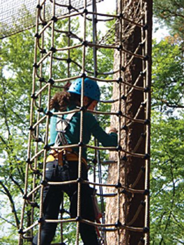 Summer Camp participant on cargo tube activity on high ropes course.