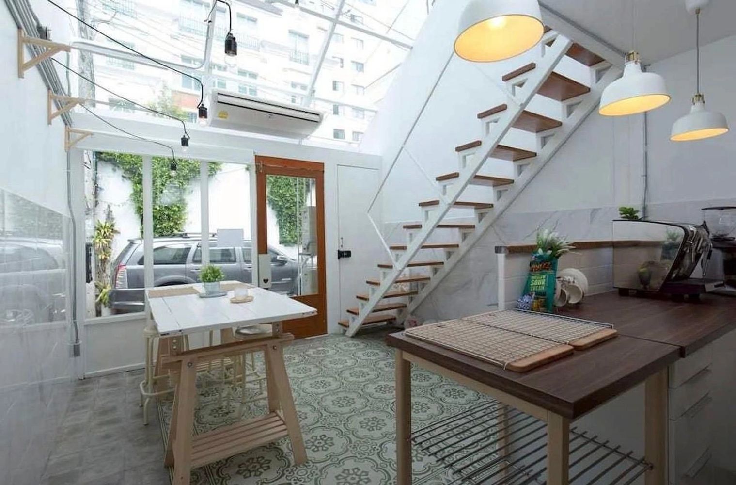 Bright kitchen with patterned floor, wooden stairs, and hanging lights.
