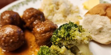 Meatballs, broccoli, mashed potatoes, and a roll