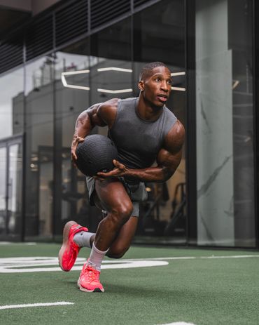 male fitness athlete performing functional exercise on turf at the gym