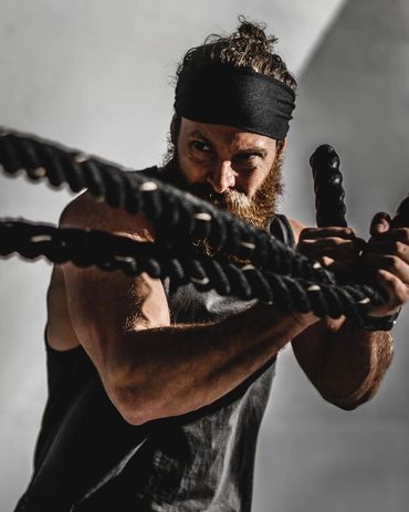 athletic male performing battle ropes exercise against concrete background