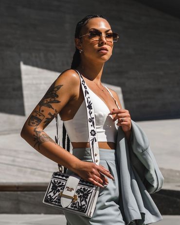 stylish woman with braided hair wearing casual business attire and holding a prada bag