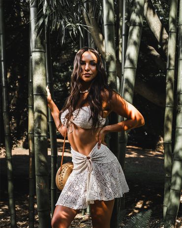 girl standing in front bamboo trees wearing beach vacation cover up swimwear