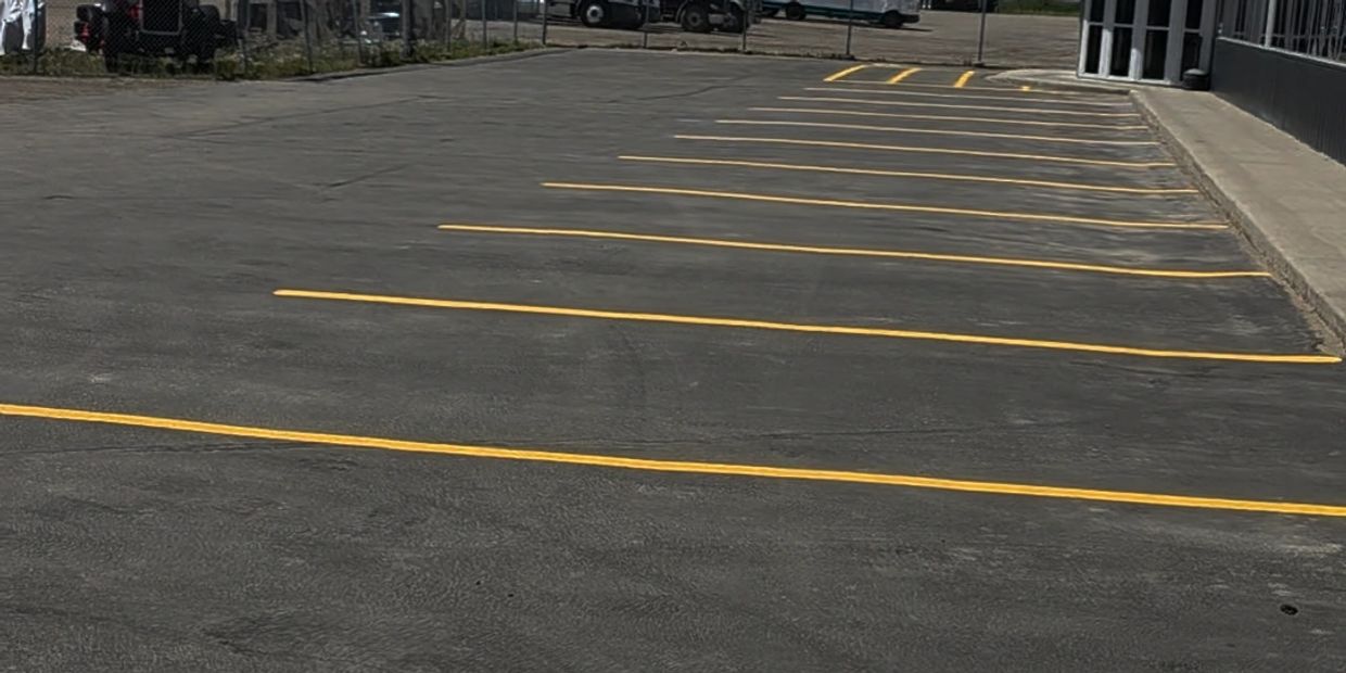 Empty parking lot with freshly painted yellow lines beside a commercial building.