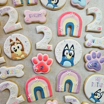 Colorful decorated cookies for a child's 2nd birthday with rainbows, paw prints, and cartoon dogs.